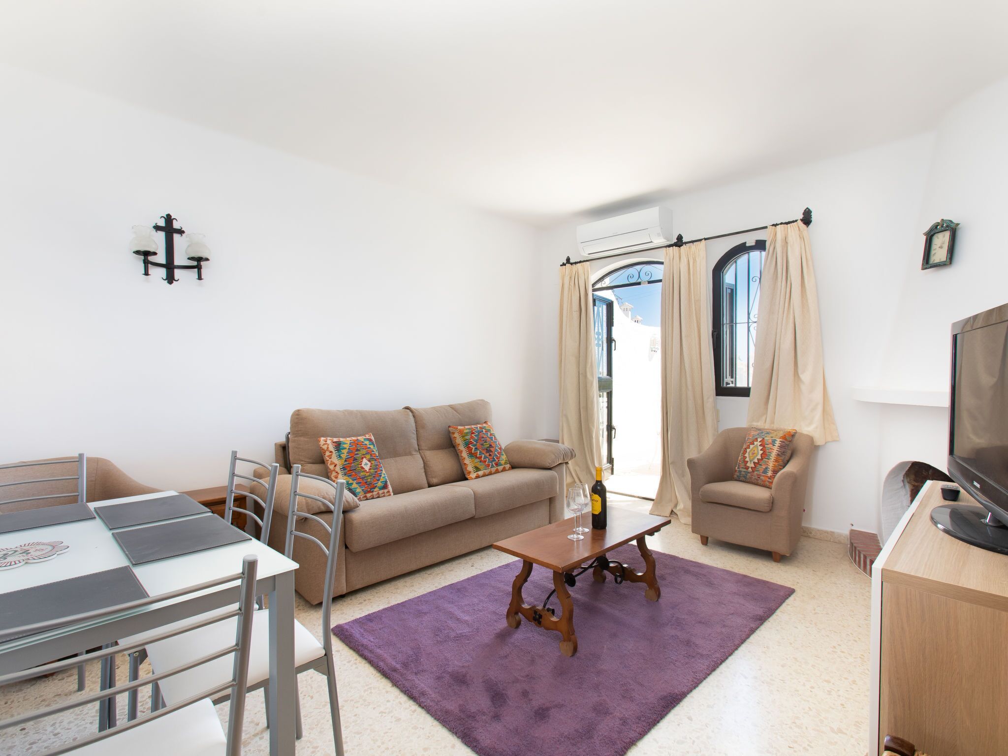 Una sala de estar con sofá, sillones, una mesa de centro, televisor y un comedor con mesa y sillas.