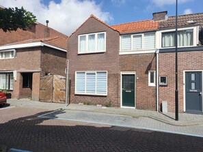 A row of two-story brick houses with a tiled roof, a gated driveway, and a clear blue sky. - Huis met Tuin in het Centrum Vlakbij de zee en Amsterdam (Beverwijk)