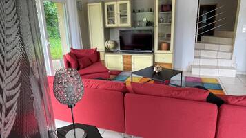 A modern living room with a red sofa, a television, and a globe on a cabinet.
