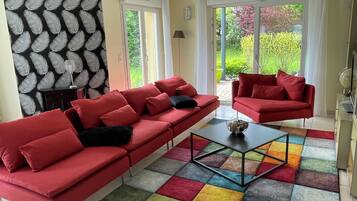 A living room with a red sofa, a coffee table, and a colorful rug.