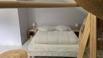 A bedroom with a bed, two bedside tables with lamps, a woven chair, and a woven rug.
