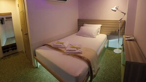 Ein ordentlich bezogenes Bett mit Handtüchern, einer Nachttischlampe und einem kleinen Tisch mit einem Buch.