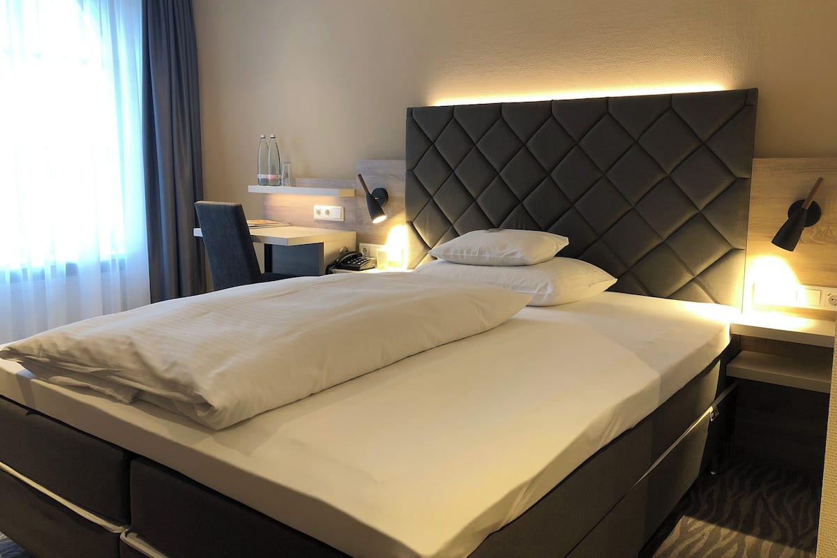 Habitación de hotel con una cama grande, un escritorio y una silla.