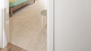 Camera d'albergo con due letti, un tavolino, una lampada a sospensione e un cartello attaccato al muro.