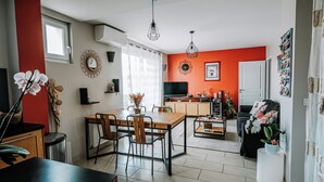A modern kitchen with a dining area, a TV, and a red accent wall.