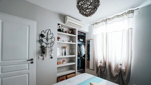 A bedroom with a bed, a wardrobe, and an air conditioning unit.