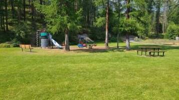 Ein Park mit einem Spielplatz, einem Picknicktisch und Bänken.