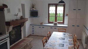 A kitchen with a dining table, chairs, a stove, a sink, and cabinets. - Gîte Chez Mamie 
A pleasant and quiet cottage by the sea (Saint-Marcouf)