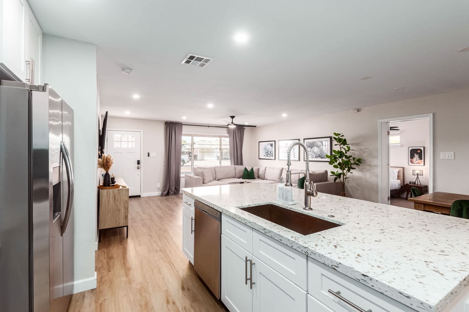 A modern kitchen with a large island, stainless steel appliances, and a dining area with a view.