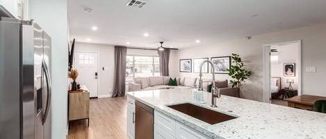 Una cocina moderna con una isla grande, electrodomésticos de acero inoxidable y un comedor con vistas.