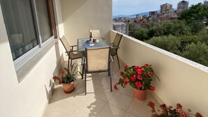 A balcony with a table and chairs, potted plants, and a view of the cityscape. - Albania Dream Holidays Accommodation (Sarandë)