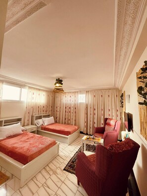 Habitación de hotel con dos camas, un sofá, un televisor y una pared decorativa.
