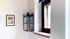 A corner room with a wooden ceiling, a window with a dark frame, a wall-mounted light fixture, and a framed picture. - Apartment on the Hill Between Gubbio and Perugia (Perugia)