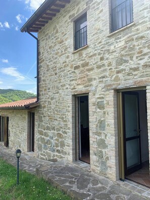 A stone building with multiple windows and doors, a tiled roof, and a stone pathway leading to the entrance. - Apartment on the Hill Between Gubbio and Perugia (Perugia)
