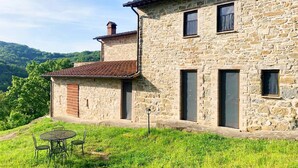 A stone house with a tiled roof, a chimney, and a small patio with a table and chairs. - Apartment on the Hill Between Gubbio and Perugia (Perugia)