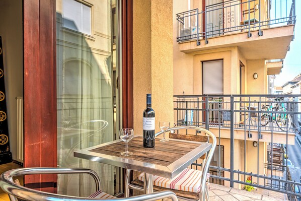 A balcony with a table, a wine bottle, and a glass. - Central Capital Apartments (Budapest)