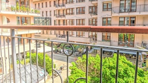 En flervåningsbyggnad med bostäder, balkonger, en innergård och utomhusområden med sittplatser.
