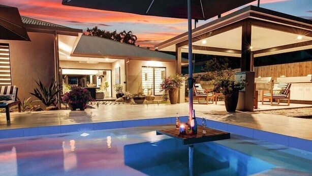 A modern outdoor pool area with a sunset view, a covered seating area, and potted plants. - 4 Bedroom Luxury House in Port Douglas (Port Douglas)