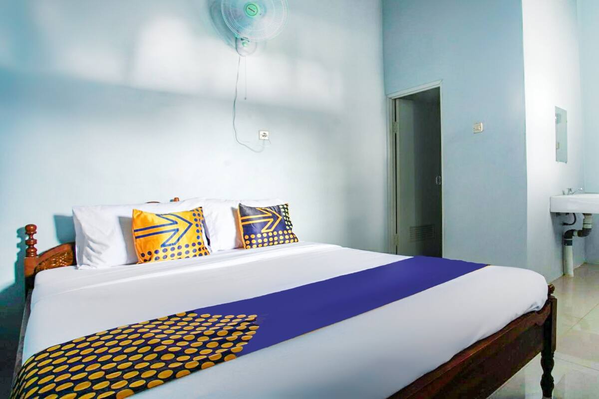 A neatly made bed with a blue and yellow bedspread, a wooden headboard, and patterned pillows.