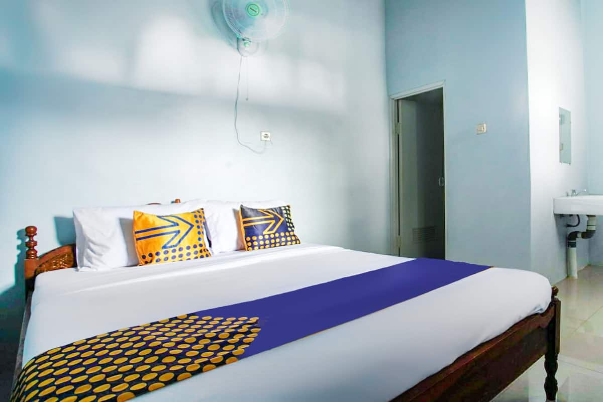 A neatly made bed with a blue and yellow bedspread, a wooden headboard, and patterned pillows.