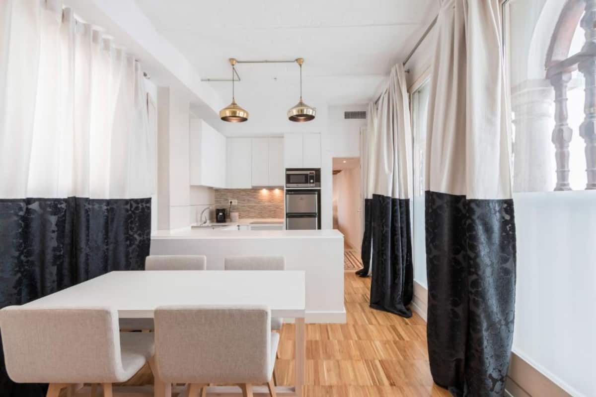 Una cocina moderna con armarios blancos, una isla central y electrodomésticos de acero inoxidable.