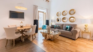 Una sala de estar moderna con una mesa de centro de vidrio, un sofá y una zona de comedor con sillas.