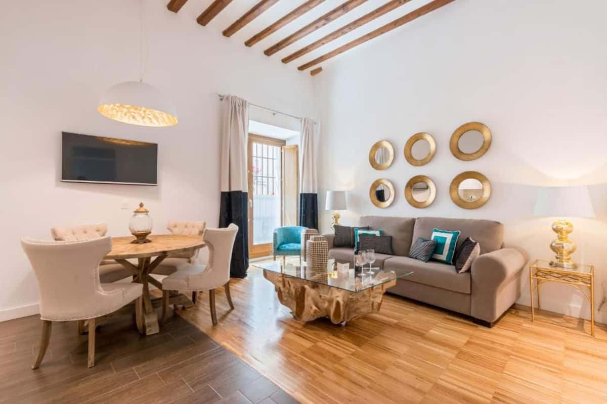 Una sala de estar moderna con una mesa de centro de vidrio, un sofá y una zona de comedor con sillas.