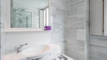 Un baño moderno con lavamanos, tocador y zona de ducha blanca.