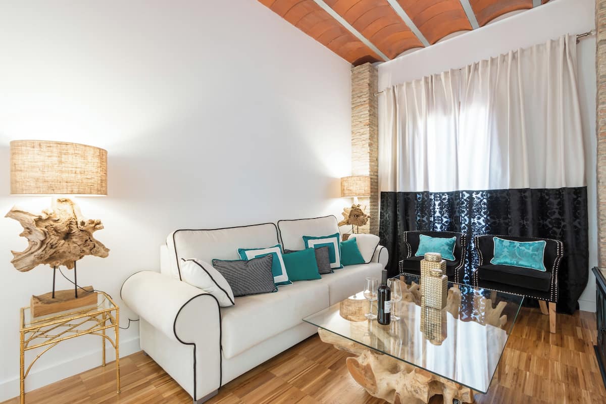 Una sala de estar moderna con un sofá blanco, una mesa de centro de vidrio y piso de madera.
