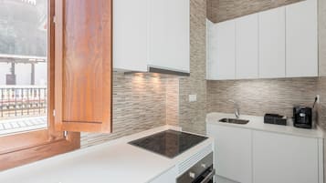 Una cucina moderna con mobili bianchi, piano cottura integrato e macchina da caffè.