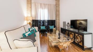 Una sala de estar moderna con un sofá, sillones, una mesa de centro y un televisor.
