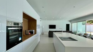 Una cocina moderna con electrodomésticos integrados, una isla grande con un lavamanos y una zona de comedor con vistas.