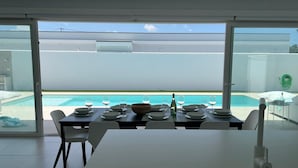 Comedor con una mesa dispuesta para seis personas, con vista a una piscina.