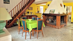 A dining area with a wooden staircase, a brick fireplace, and a dining table with chairs.