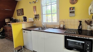 A kitchen with a yellow wall, a window, a sink, a dishwasher, and a microwave.