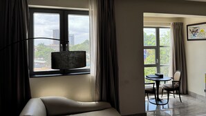 A hotel room with a bed, a desk, a chair, and a view of the outside. - The Palms by Eagles Airport Residential (Accra)