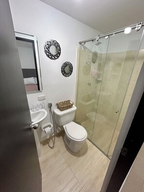 Un baño con inodoro, bidé y ducha con mampara de vidrio.