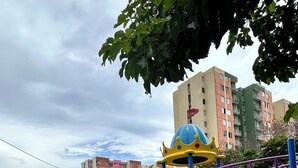A playground with a yellow slide and various play structures, surrounded by buildings and trees. - Lindo apartamento 3 habitaciones (San José de Cúcuta)
