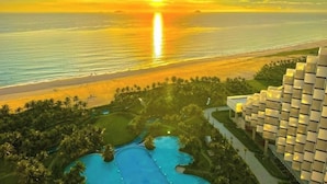 Un resort con zona de piscina, playa y vista al atardecer.
