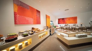 Montaje de bufé con diversos alimentos y un diseño interior moderno, que incluye pinturas abstractas en las paredes.