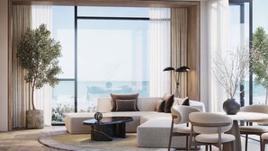 A modern living room with a sofa, chairs, a coffee table, and large windows offering a view of the ocean. - Delano Dubai (Dubai)