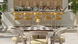 An outdoor bar area with a wooden wall, bar stools, and a variety of bottles. - Delano Dubai (Dubai)
