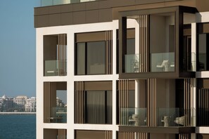 A modern building with multiple balconies, large windows, and a view of the sea.