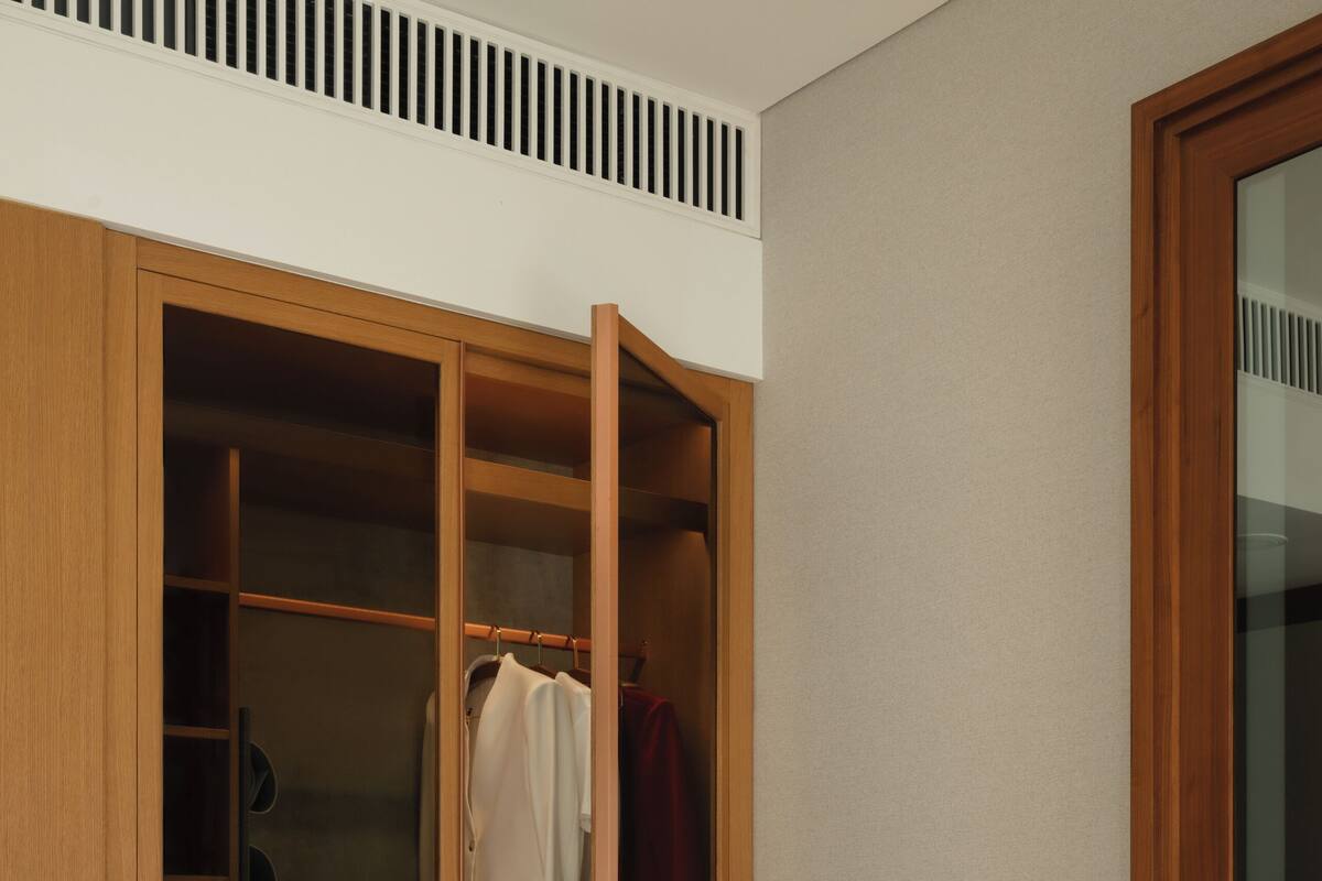 A wooden wardrobe with a mirror, a bench, and a small table with a decorative item.