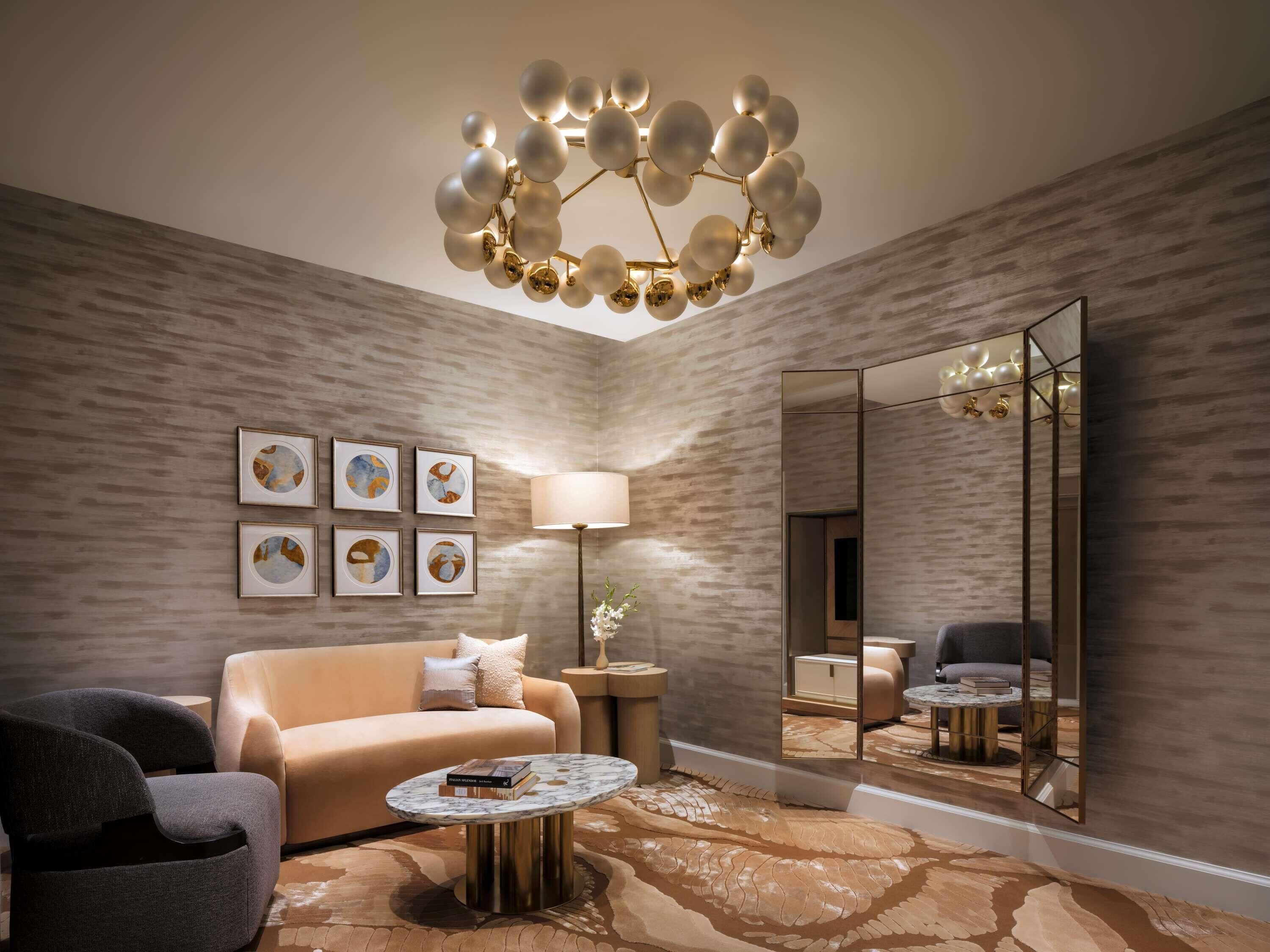 A modern living room with a sofa, armchair, round coffee table, and a unique spherical chandelier.