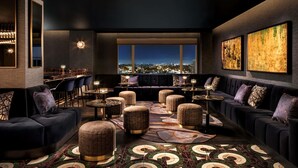 A modern lounge with dark sofas, round tables, and a patterned floor.