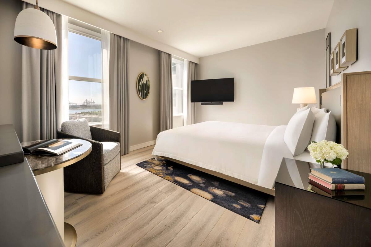 Een moderne hotelkamer met een groot bed, een bureau, een stoel, een televisie en uitzicht over de stad.