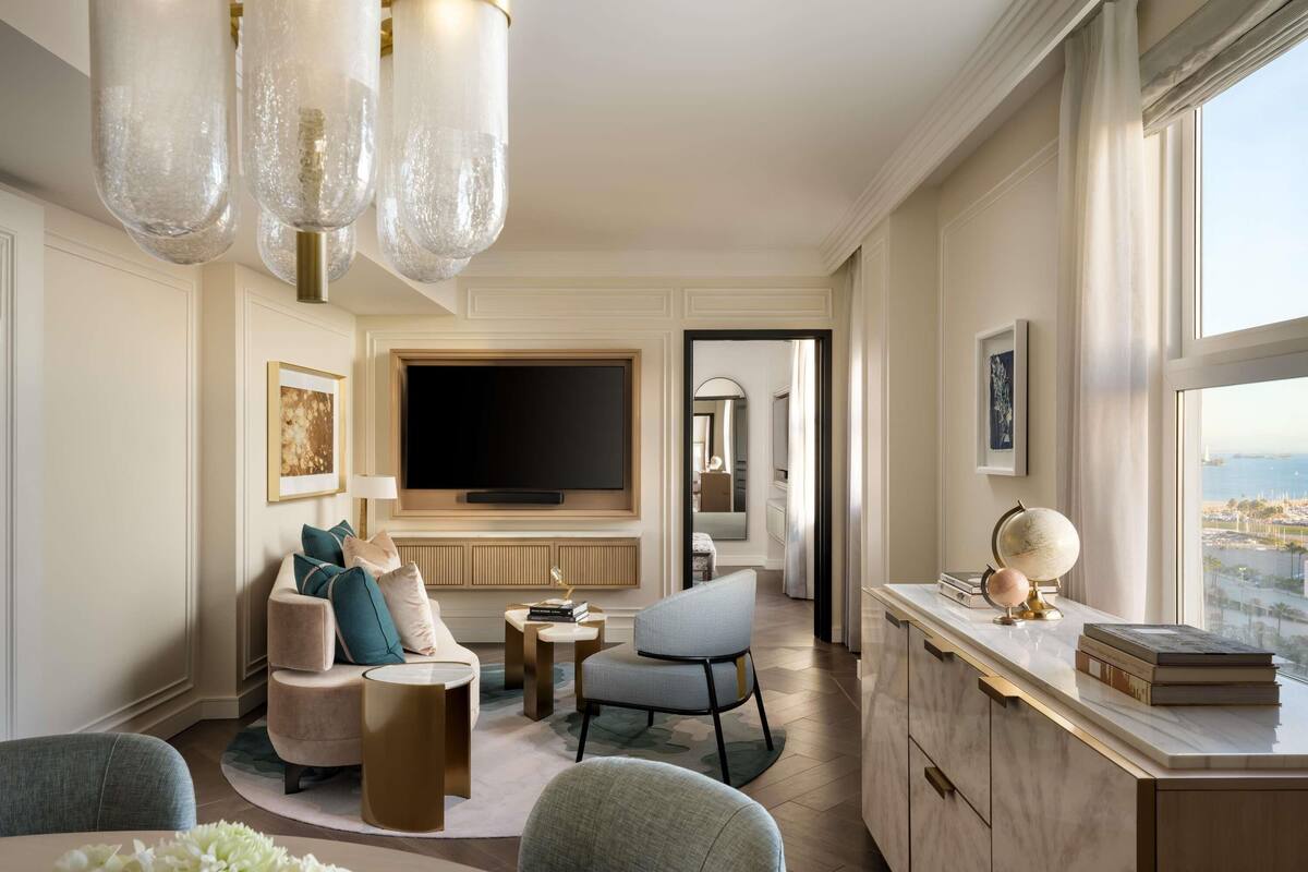 Een moderne woonkamer met een flatscreen televisie, comfortabele zitplaatsen, een eethoek en uitzicht op de stad.