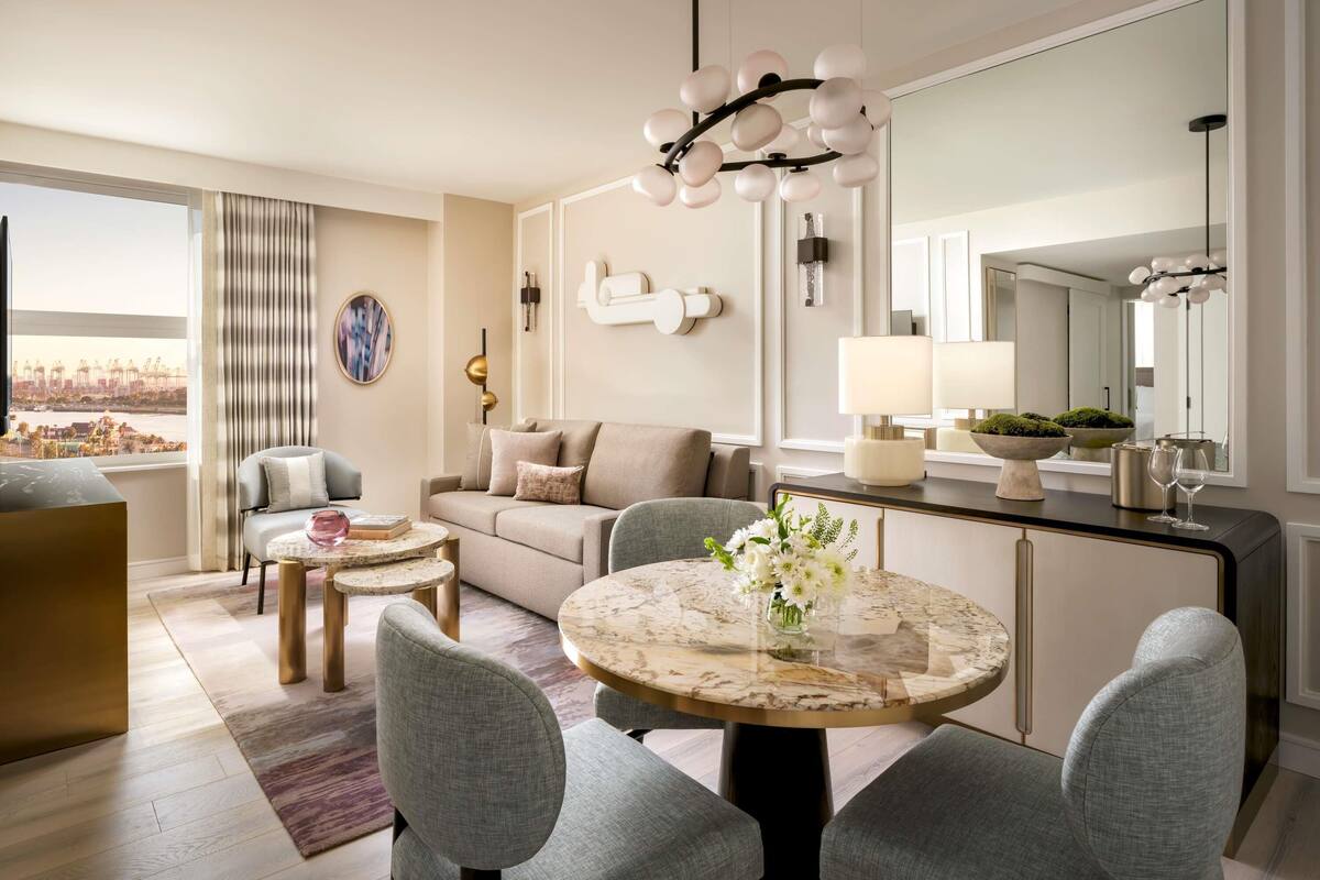 Een moderne woonkamer met een bank, twee ronde tafels en een grote spiegel.
