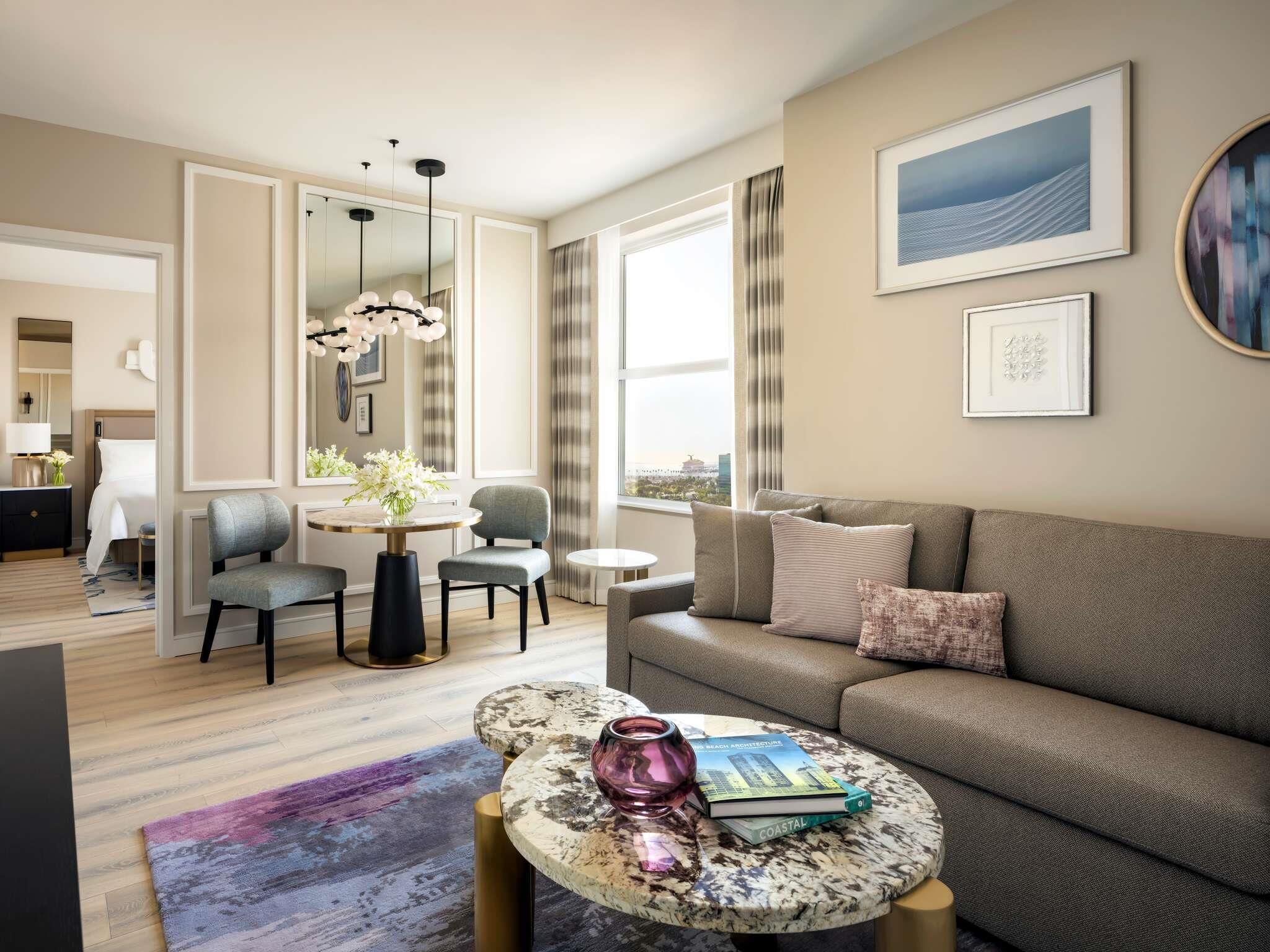Una sala de estar moderna con un sofá, una mesa de comedor y una mesa auxiliar con un libro y un jarrón.